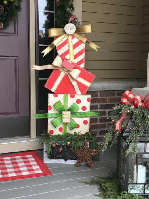 Decoración navideña de una puerta con regalos afuera 