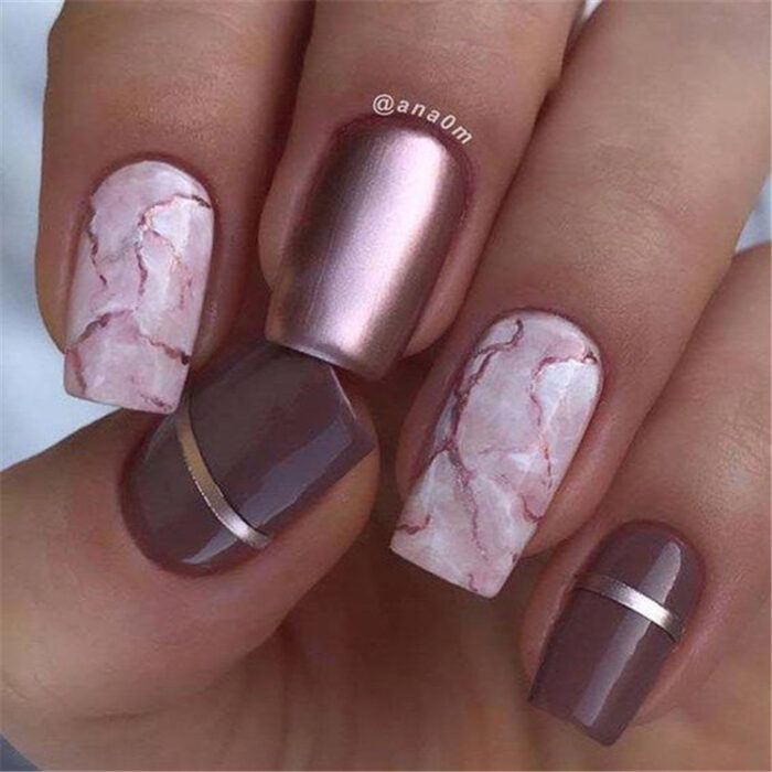 Chica con las uñas en un diseño metálico de color rosa con diseños en marmol