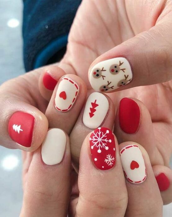 Uñas pintadas en tonos blanco y rojo con difuras navideñas de copos de nieve; diseños manicuras navideñas