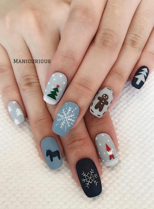 Uñas en color base gris y azul decoradas con motivos navideños; diseños manicuras navideñas