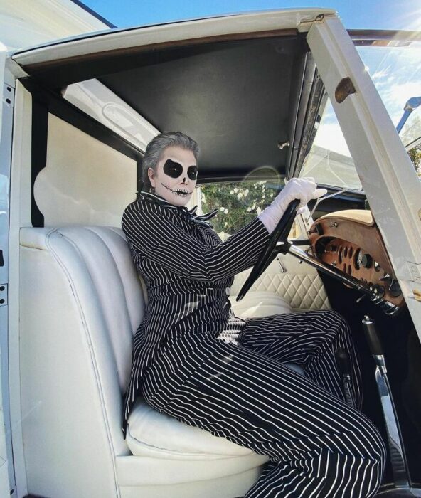 Kris Jenner posando en un automóvil blanco al volante disfrazada como Jack  skellington