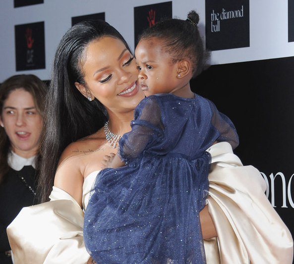 Rihanna sosteniendo en brazos a su sobrina mientras ambas están en una alfombra roja 