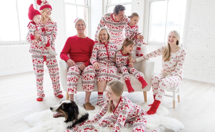 Familia completa en la sala, usando la misma pijama de navidad riendo y disfrutando