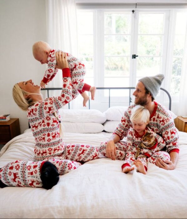 Familia sentados sobre la cama, usando la misma pijama disfrutando del momento