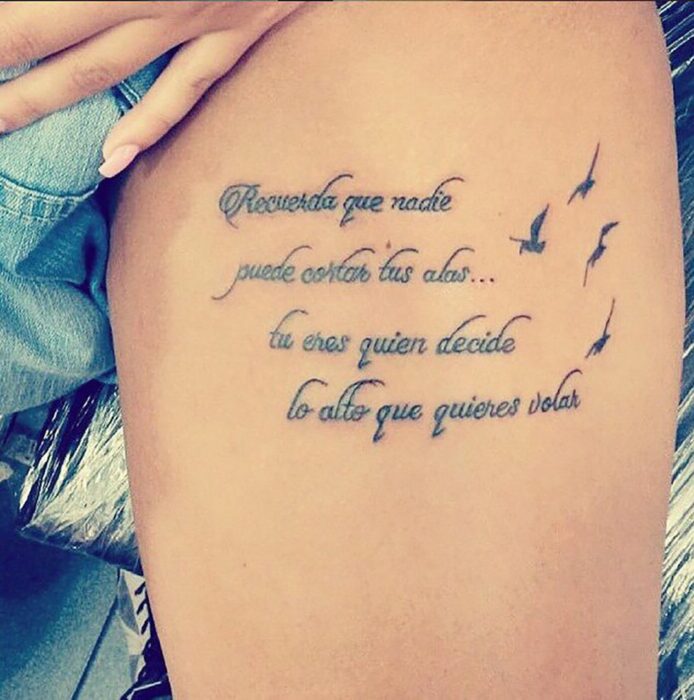 Chica con un tatuaje en el muslo en forma de frase en español