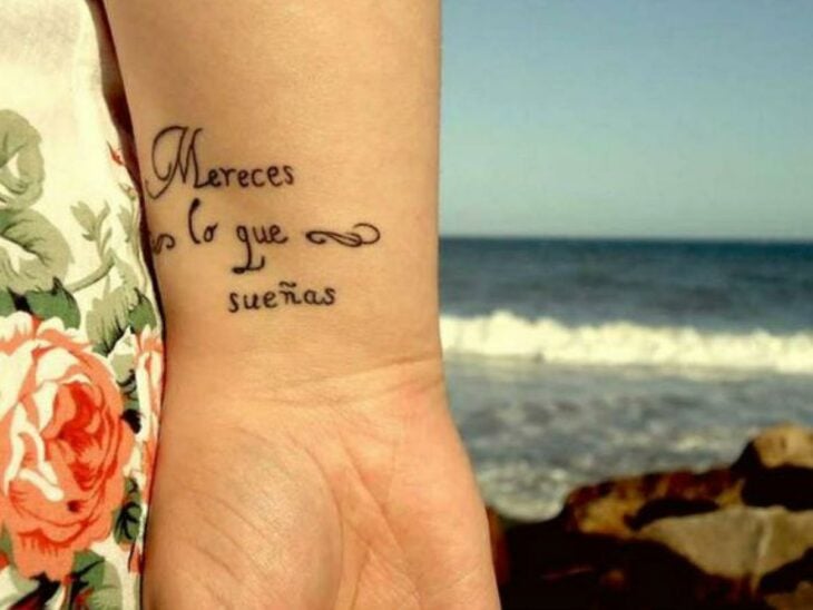 Chica con un tatuaje en la muñeca en forma de frase en español