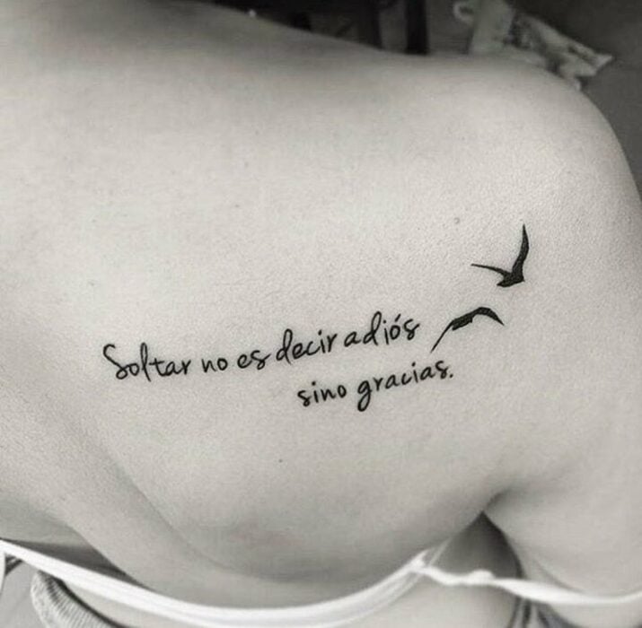 Chica con un tatuaje en la espalda en forma de frase en español