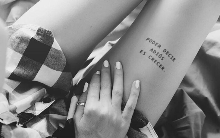 Chica con un tatuaje en el muslo en forma de frase en español