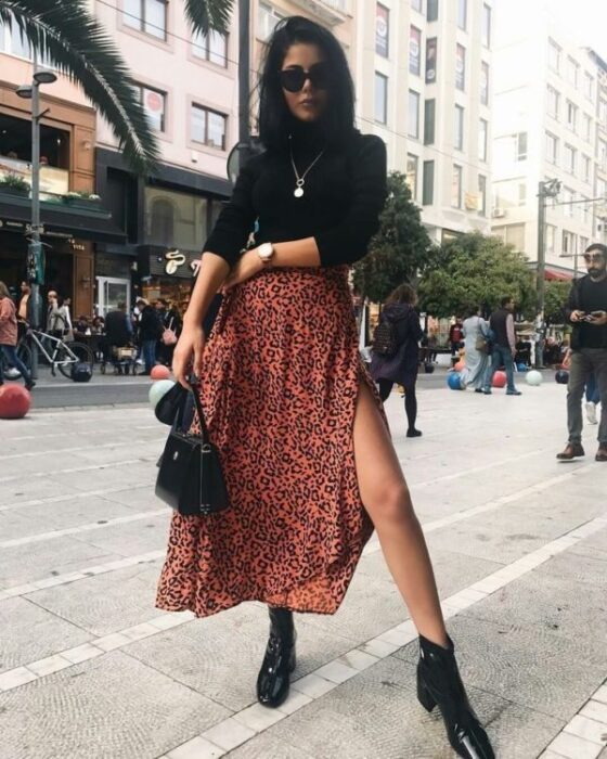 Chica con maxi falda naranja y camisa de cuello alto negro;  Ideas para usar camisa de cuello alto