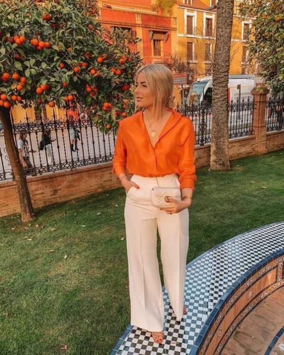 Chica usando una blusa de satín en color naranja con pantalón sastreIdeas para usar color naranja en tu outfit