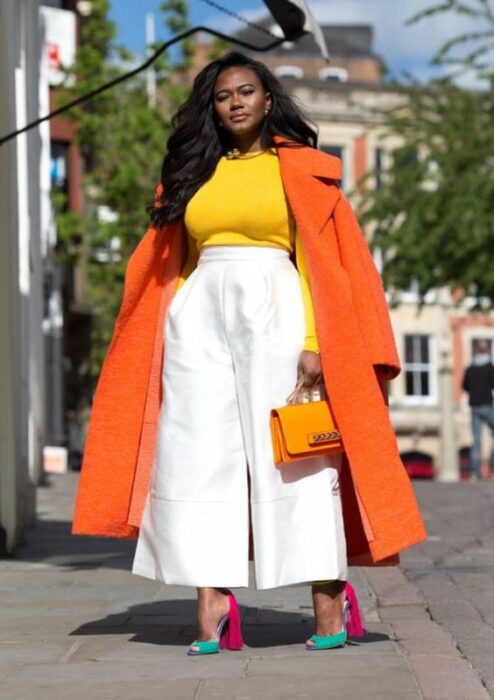 Chica llevando pantalón blanco con gabardina en naranja; Ideas para usar color naranja en tu outfit