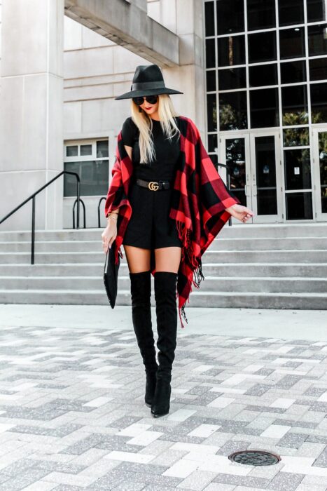 Chica usando un vestido de color negro con botas largas, sombrero y un poncho de color rojo con negro