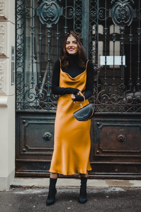 Chica usando un vestido de color mostaza con una blusa cuello de tortuga y botines 