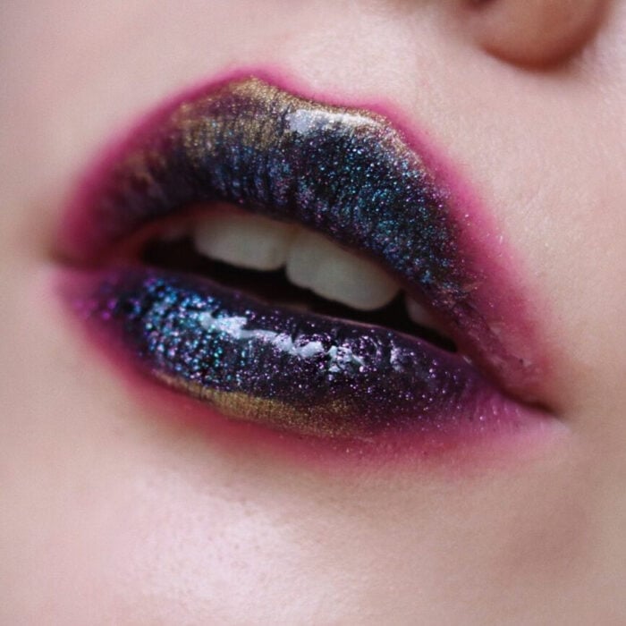 Künstlerisches Lippen Make-up von Maskenbildnerin Tatiana Rose;  Mund mit Ölteppich oder Petroleum-Effekt Lippenstift Farbe schwarz, lila, goldgrün verschwommen wie Lutscher Lippenstift mit rosa