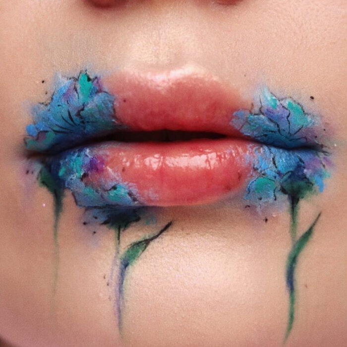 Maquillaje artístico de labios por maquilladora Tatiana Rose; boca con labial color carne y dibujos de flores azules en las orillas