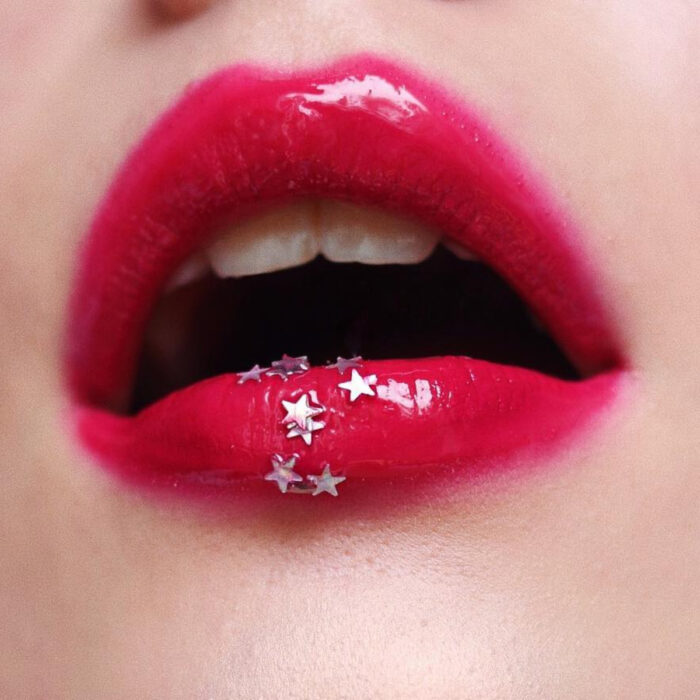 Maquillaje artístico de labios por maquilladora Tatiana Rose; boca con labial rojo cereza y gloss, brillos en forma de estrella