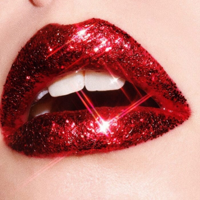 Maquillaje artístico de labios por maquilladora Tatiana Rose; boca con labial color rojo fuerte y con brillos rojos