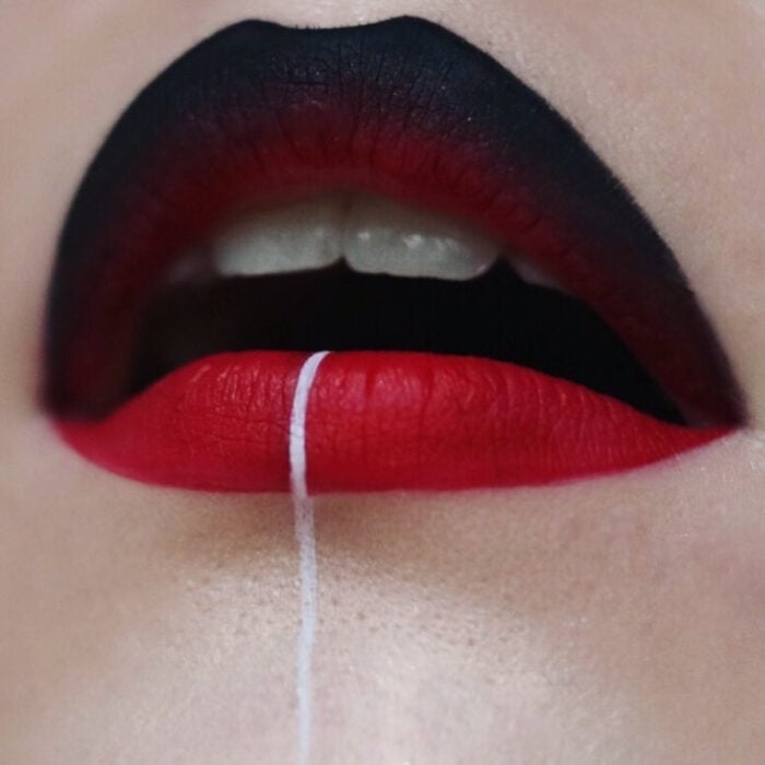 Künstlerisches Lippen Make-up von Maskenbildnerin Tatiana Rose;  Mund mit Lippenstift in zwei Farben, über schwarz und unter rot verblassend, weiße Linie in der Mitte