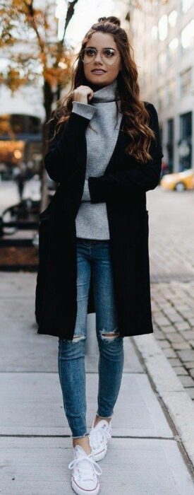 Chica usando jeans con tenis blancos, suéter de cuello alto y abrigo negro largo