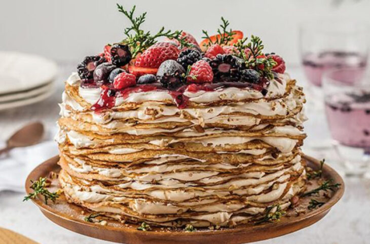 Pastel de Navidad de crepas con relleno de crema batida con decorado de frutos rojos