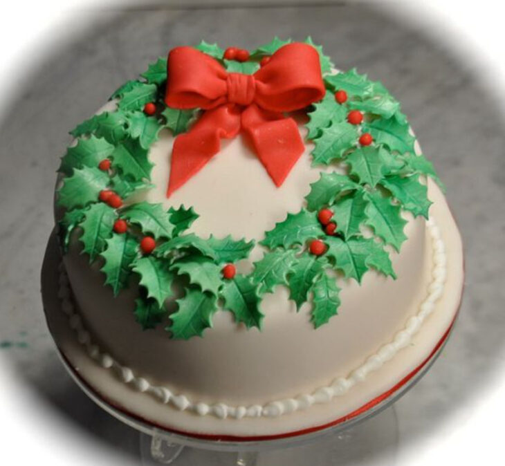 Pastel de Navidad de vainilla con decorado de corona de navidad y moño rojo