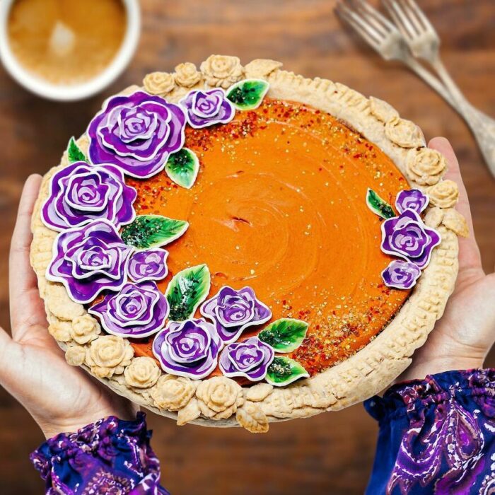 Pay de calabaza con decoración de flores moradas con hojas verdes 