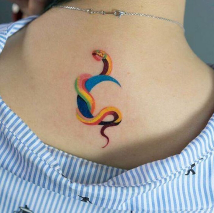 Tatuaje de serpiente en tinta de colores, entrelazada a una luna sobre la nuca