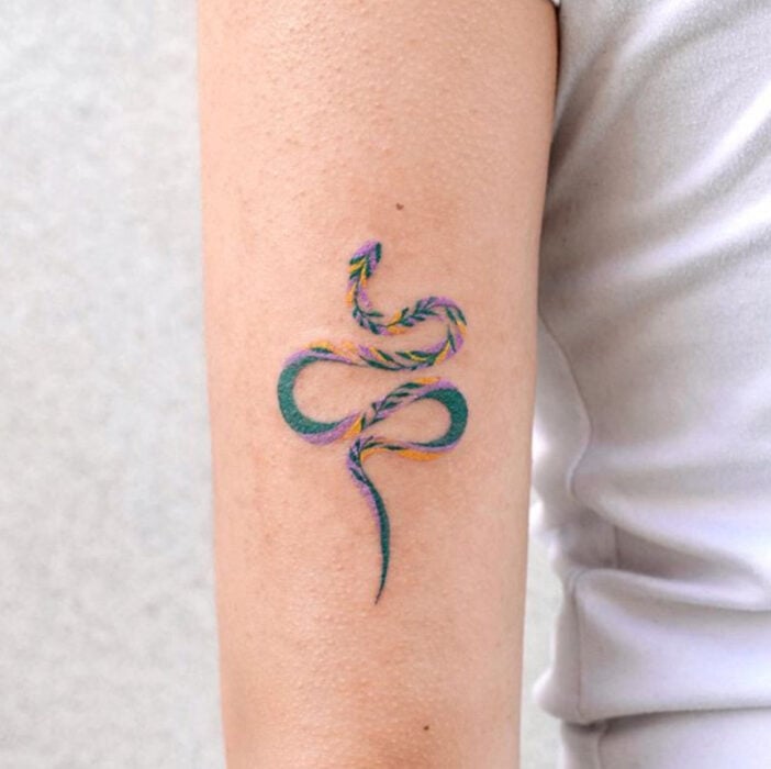 Tatuaje de una serpiente en tinta de varios colores en la zona del antebrazo