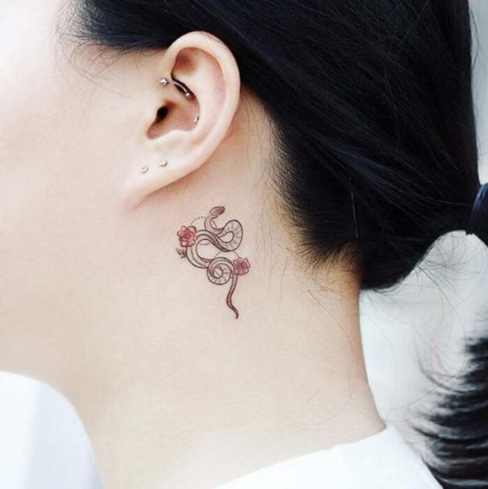 Kleine schwarze Tinte Schlangen Tattoo mit roten Blumen hinter dem Ohr 