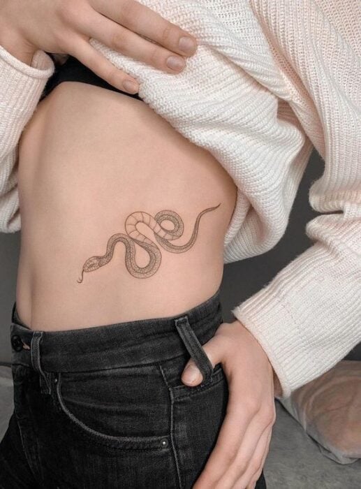 Tatuaje de serpiente en tinta negra sobre la cintura