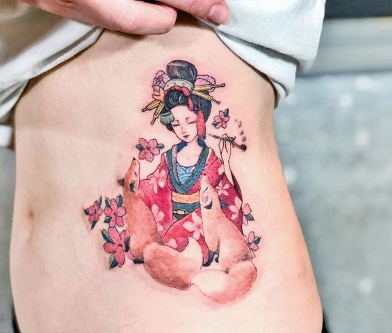 Tatuaje de geisha rodeada de tres zorros y flores de cerezo