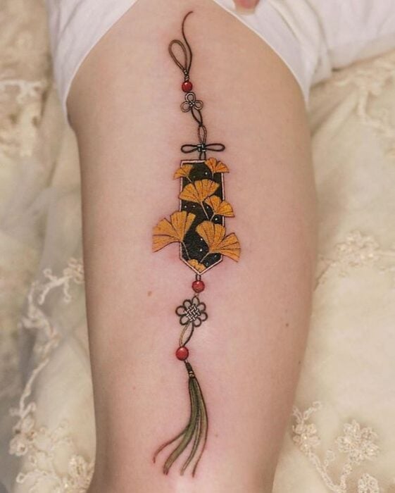 Tatuaje de colgante asiático en el brazo para mujer