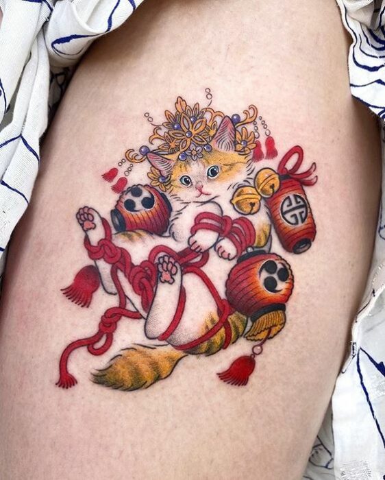 Tatuaje de gatito blanco con amarillo envuelto en lazos rojos y 