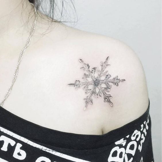 Chica con tatuaje en forma de copo de nieve; Tatuajes miniatura para las que aman la Navidad
