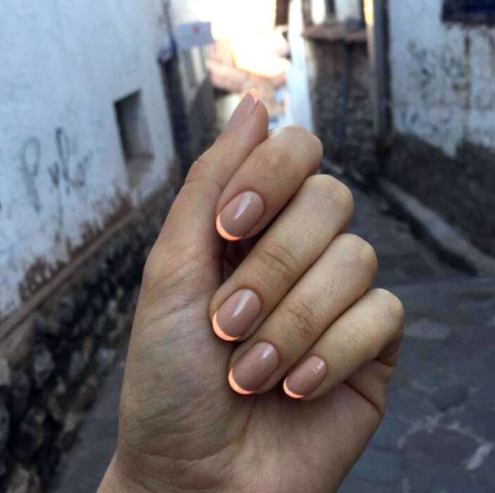 Manicura en fondo nude con estilo frances en color naranja