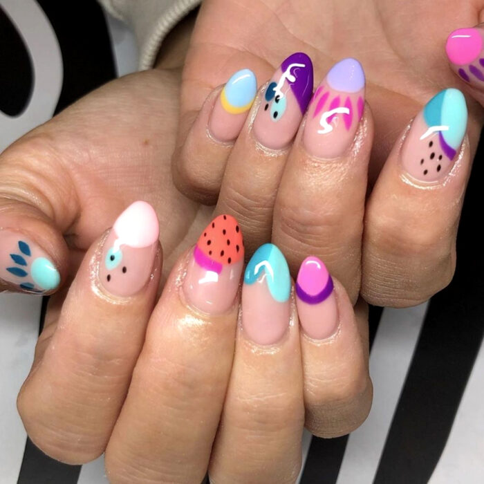 Diseños bonitos de manicura coloridos; uñas largas en forma de almendra pintadas con esmalte nude rosa y figuras azules, blancas, anaranjadas, rosas, moradas y puntitos negros