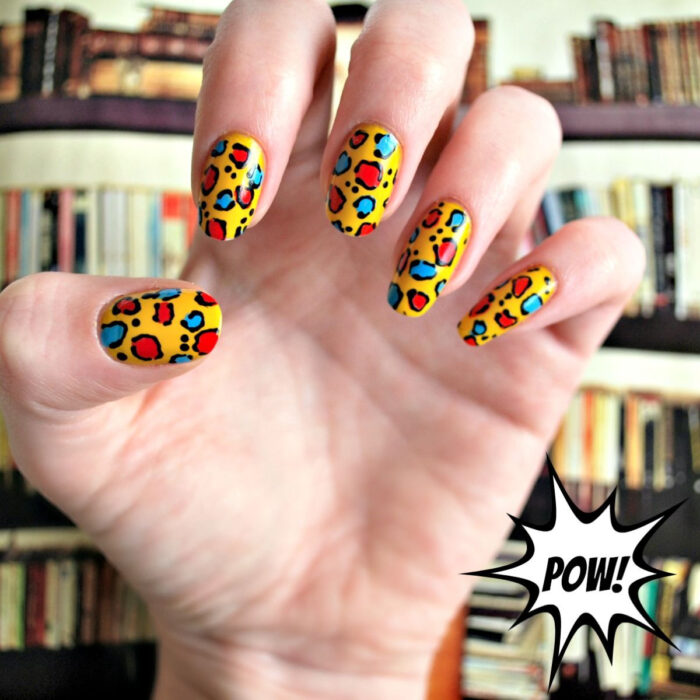 Diseños bonitos de manicura coloridos; manos de mujer con uñas largas redondas pintadas con esmalte de colores, base amarilla con diseño de animal print de leopardo rojo, negro y azul