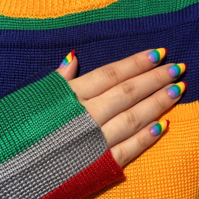 Diseños bonitos de manicura coloridos; uñas largas en forma de almendra pintadas con esmalte de colores del arcoíris, morado, azul, verde, amarillo, anaranjado y rojo