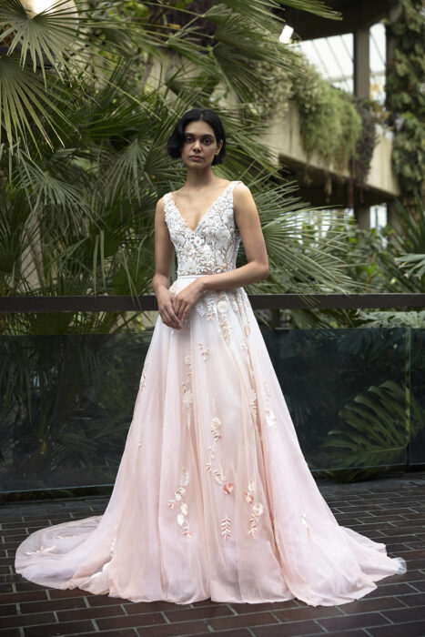 Chica usando un vestido de novia en color rosa con detalles brillantes en flores y mariposas 