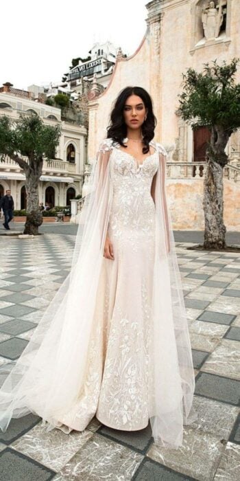 Chica usando un vestido de novia con una capa larga y detalles en brillos