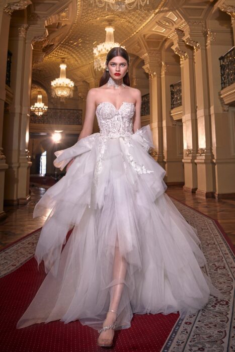 Chica usando un vestido de novia de color morado con diferentes capas y detalles en brillos que caen desde el top hasta la falda 