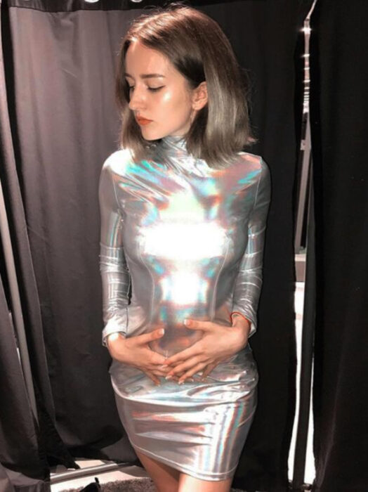 Vestido iridiscente, holográfico con cuelo y mangas, mujer de cabello corto y castaño rubio