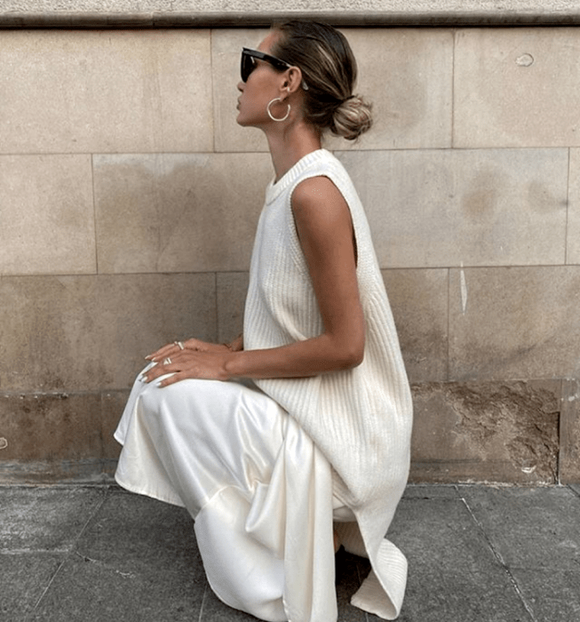 chica rubia con lentes de sol, suéter blanco sin mangas tejido, falda de satén blanca