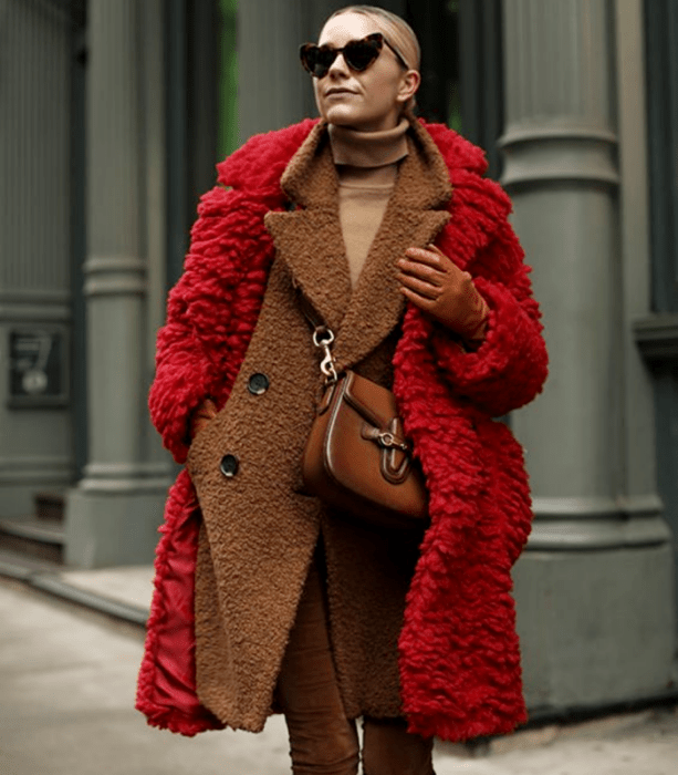 chica rubia usando lentes de sol, suéter beige de cuello alto, abrigo café teddy coat, abrigo largo afelpado rojo y bolso de piel café