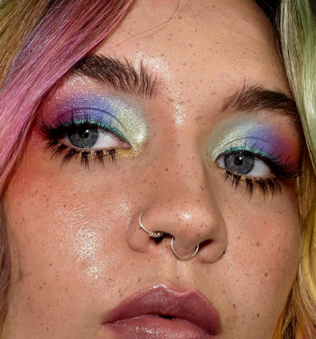 blondes Mädchen, das Retro-Make-up im Vintage-Stil der 60er und 70er Jahre mit leuchtend blauen, grünen, rosa und lila Schatten trägt, mit falschen Wimpern und Glitzer