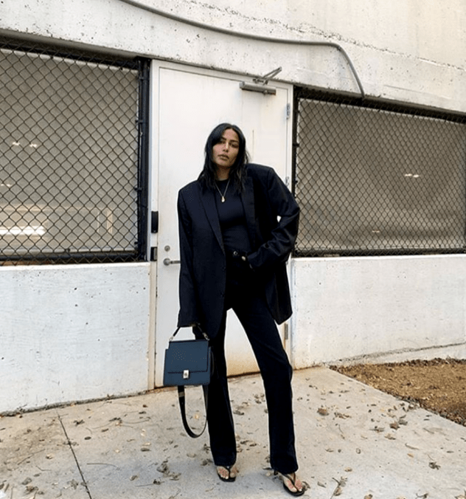 chica de cabello oscuro usando un top negro, blazer oversized negro, pantalones de vestir negros, sandalias de tacón negras, bolso de mano negro