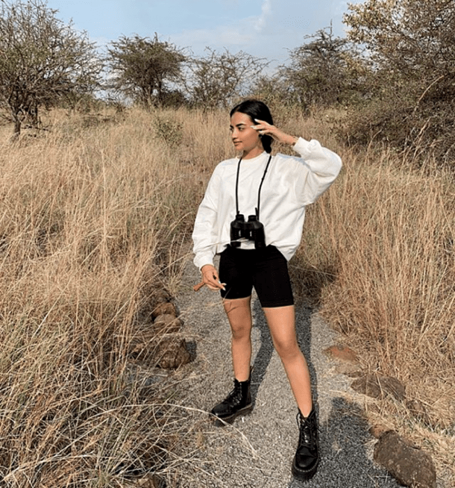 chica de cabello oscuro usando una sudadera blanca oversized, shorts de ciclismo negros, botines de plataforma y suela gruesa negros