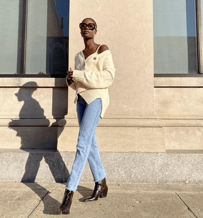 chica morena con lentes de sol rojos, top blanco de tirantes, cárdigan tejido beige, jeans rectos a la cintura, botines cafés de tacón