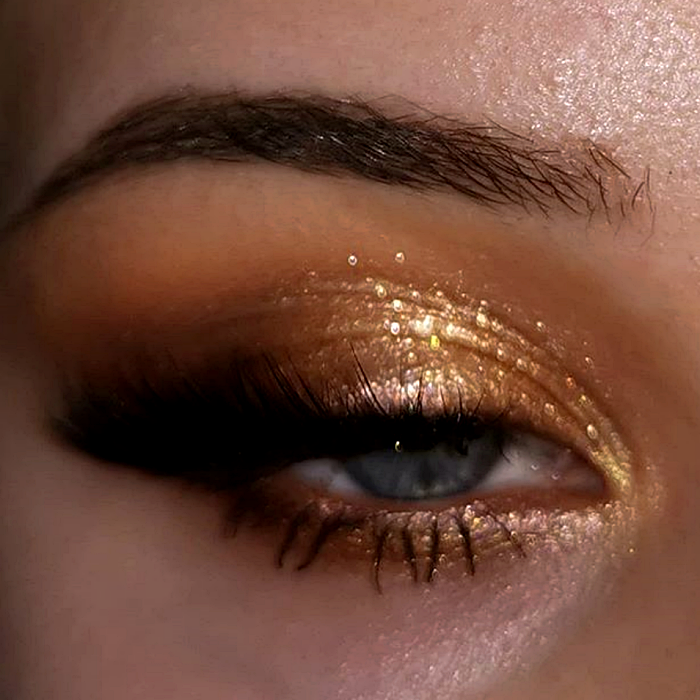 maquillaje de ojos con sombras doradas, amarillas, naranjas y cafés estilo foxy eyes, delineado negro y pestañas postizas