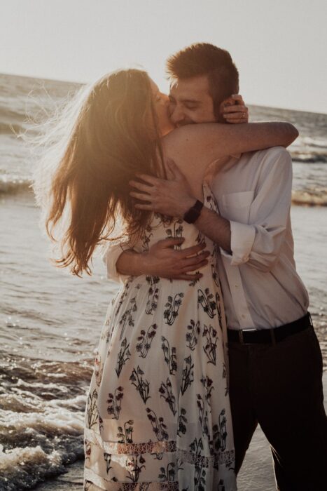 Pareja abrazándose disfrutando de un atardecer en la playa